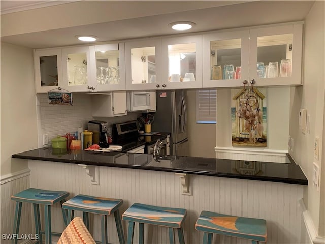 bar featuring decorative backsplash, white cabinetry, sink, and appliances with stainless steel finishes