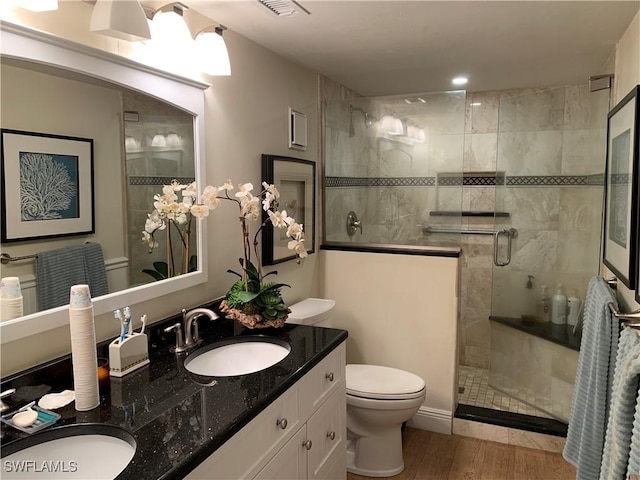 bathroom with a shower with door, vanity, wood-type flooring, and toilet