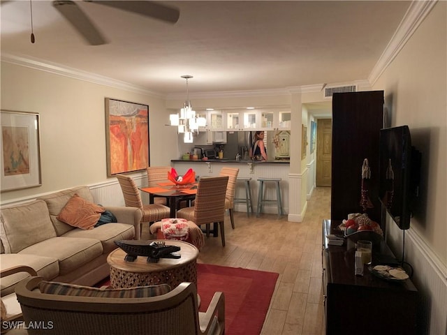 dining room with ceiling fan with notable chandelier, light hardwood / wood-style flooring, and crown molding