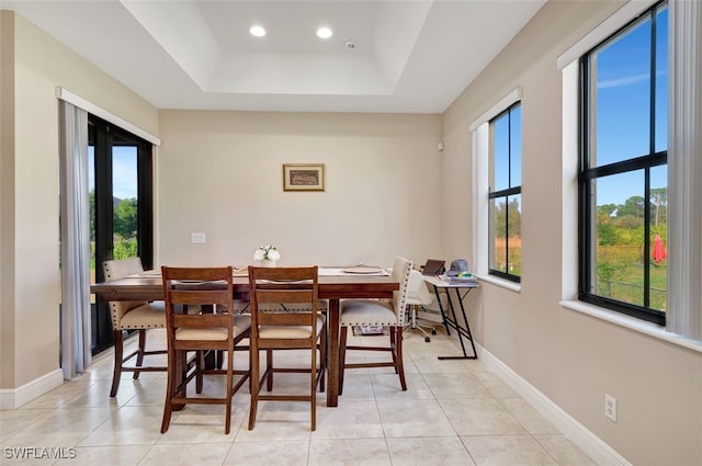 tiled dining room with a raised ceiling