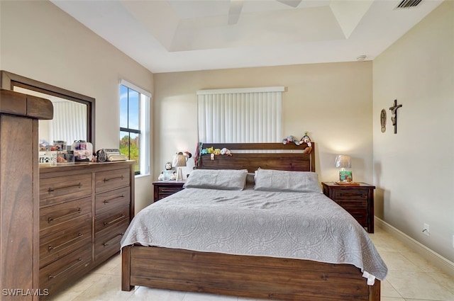 tiled bedroom featuring ceiling fan and a raised ceiling