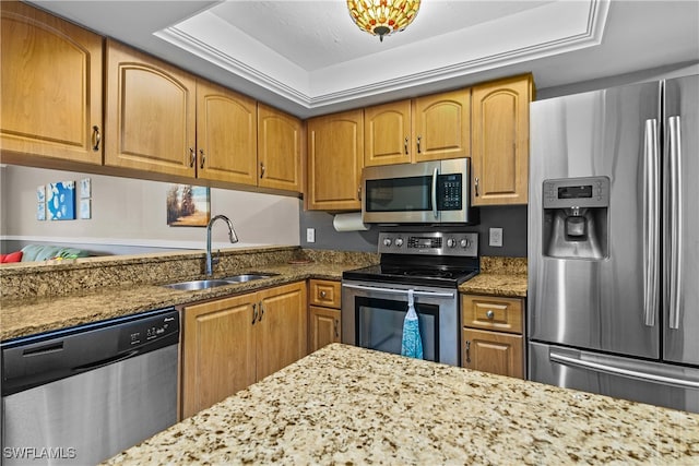 kitchen featuring light stone counters, sink, stainless steel appliances, and a raised ceiling