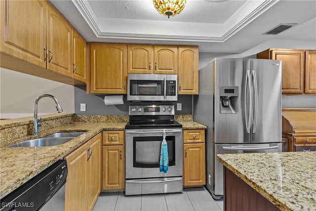 kitchen with a raised ceiling, sink, stainless steel appliances, and light stone counters