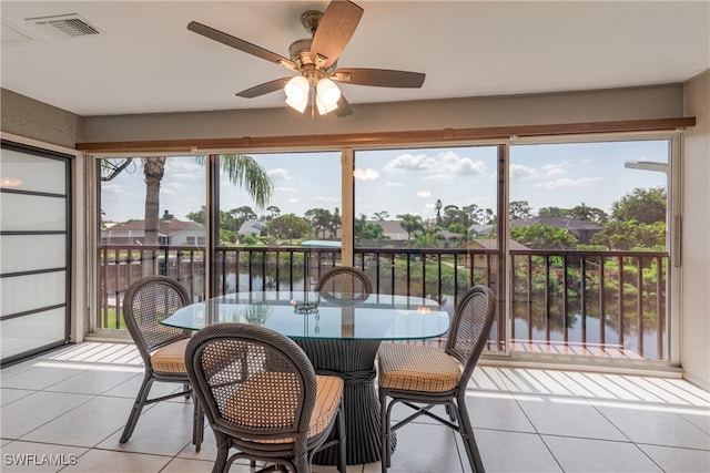 sunroom featuring a water view, ceiling fan, and a wealth of natural light