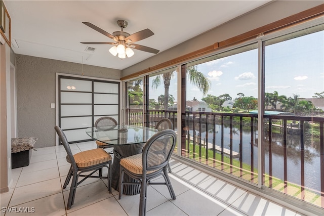 sunroom / solarium featuring a water view and ceiling fan