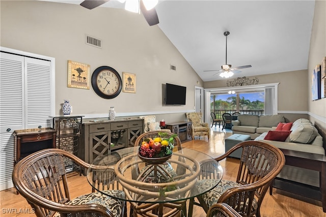 dining space with light hardwood / wood-style floors, ceiling fan, and high vaulted ceiling