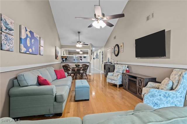 living room with light hardwood / wood-style flooring, ceiling fan, and high vaulted ceiling