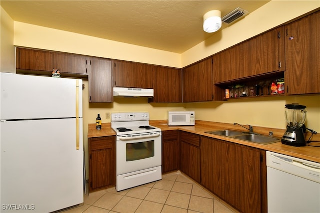 kitchen featuring a textured ceiling, sink, white appliances, and light tile patterned flooring