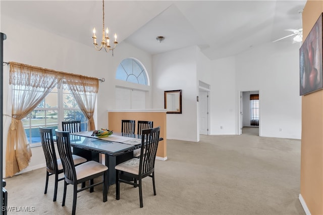 dining space with a towering ceiling, light colored carpet, and ceiling fan with notable chandelier