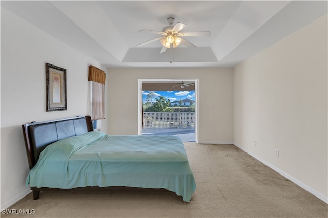 bedroom featuring light carpet, a raised ceiling, ceiling fan, and access to exterior