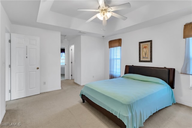 carpeted bedroom featuring ensuite bathroom, ceiling fan, and a raised ceiling