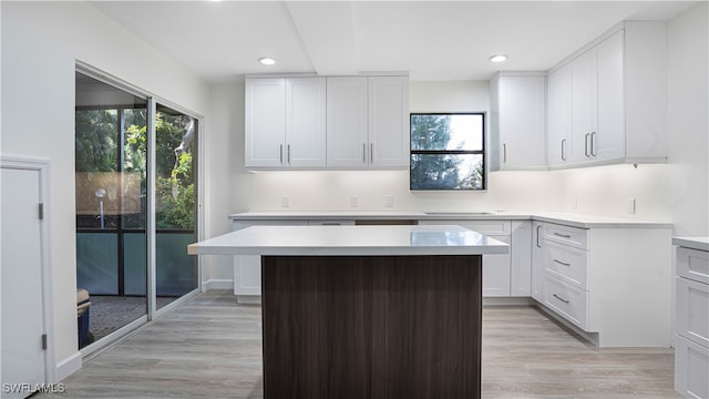 kitchen with white cabinets, a center island, a healthy amount of sunlight, and light hardwood / wood-style flooring