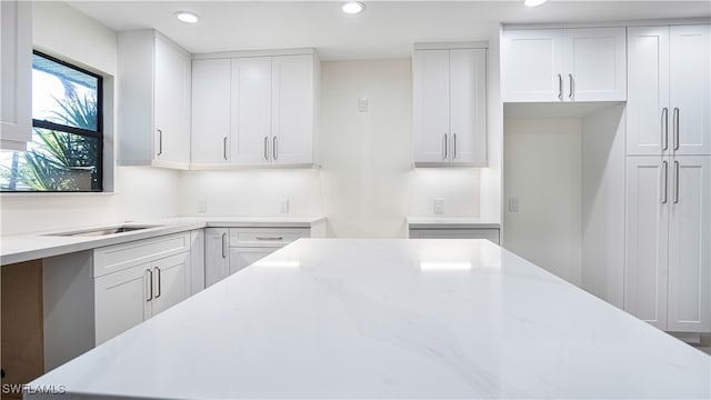 kitchen featuring white cabinets and light stone counters