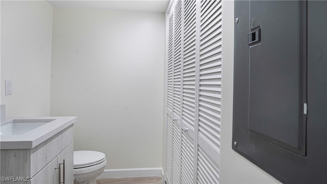 bathroom featuring a closet, vanity, toilet, and baseboards