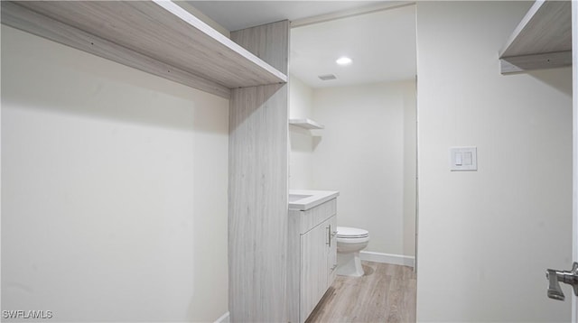 bathroom featuring baseboards, vanity, toilet, and wood finished floors