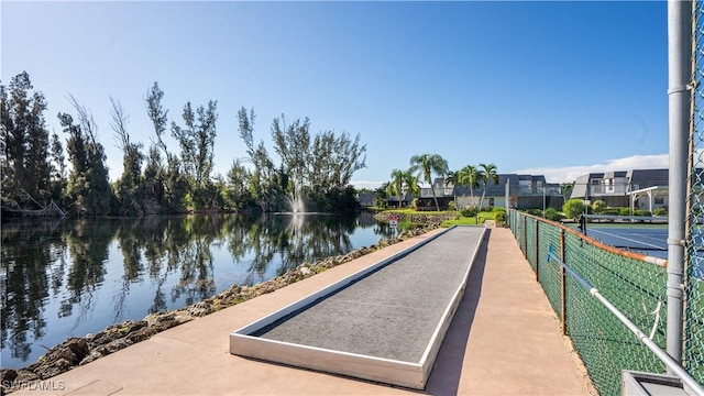 surrounding community with a water view and fence