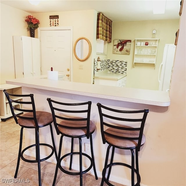 kitchen featuring a kitchen bar, kitchen peninsula, and light tile patterned flooring