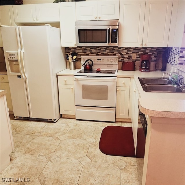 kitchen with sink, white appliances, white cabinets, and tasteful backsplash