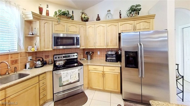 kitchen with sink, backsplash, light brown cabinetry, light tile patterned floors, and appliances with stainless steel finishes