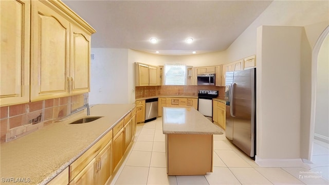 kitchen featuring light brown cabinets, stainless steel appliances, a kitchen island, and tasteful backsplash