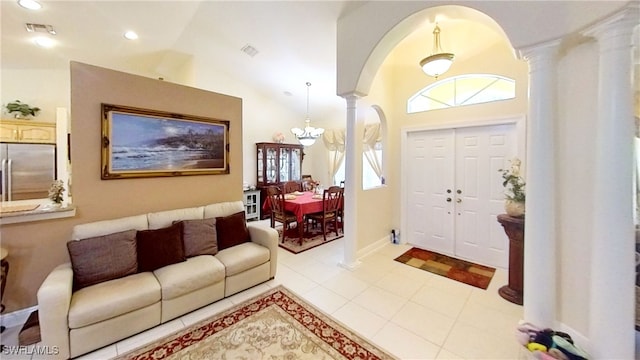 entrance foyer featuring a chandelier, light tile patterned floors, high vaulted ceiling, and ornate columns