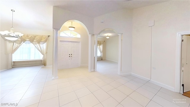 tiled foyer entrance featuring ornate columns and an inviting chandelier