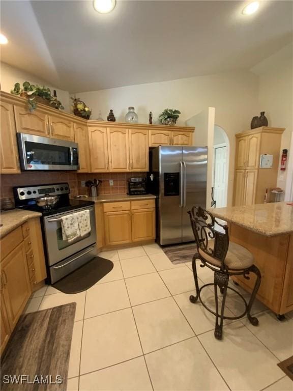 kitchen with backsplash, light tile patterned flooring, stainless steel appliances, and lofted ceiling