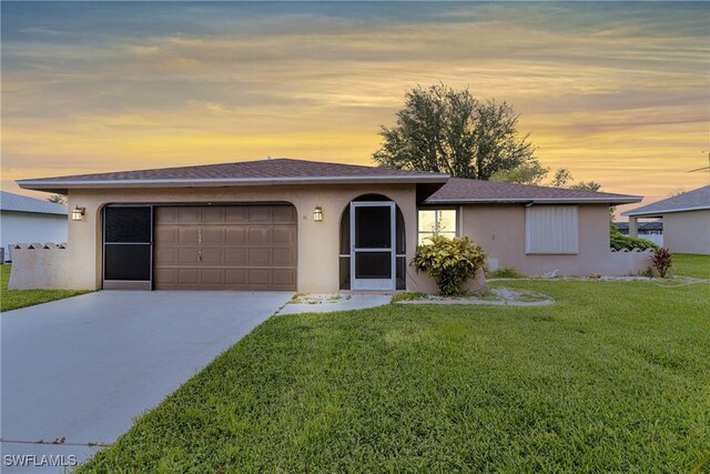 single story home with concrete driveway, an attached garage, a lawn, and stucco siding