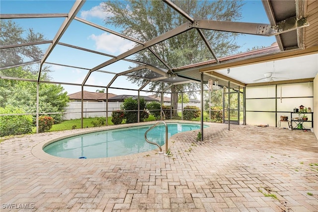 view of swimming pool featuring glass enclosure, a ceiling fan, and a patio