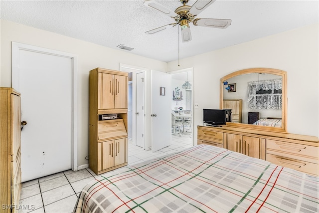 bedroom featuring light tile patterned floors, a ceiling fan, visible vents, and a textured ceiling