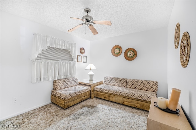 carpeted living room featuring baseboards, a textured ceiling, and ceiling fan