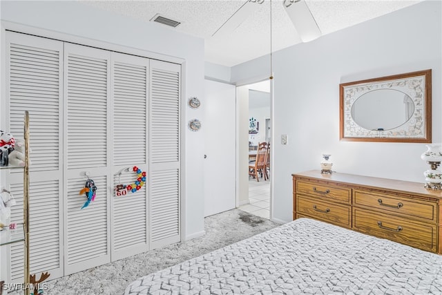 carpeted bedroom featuring a closet, visible vents, a textured ceiling, and baseboards