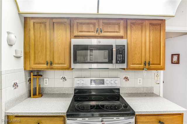 kitchen featuring light countertops, backsplash, brown cabinets, and appliances with stainless steel finishes