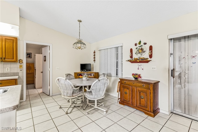 dining area with light tile patterned floors, a textured ceiling, and vaulted ceiling