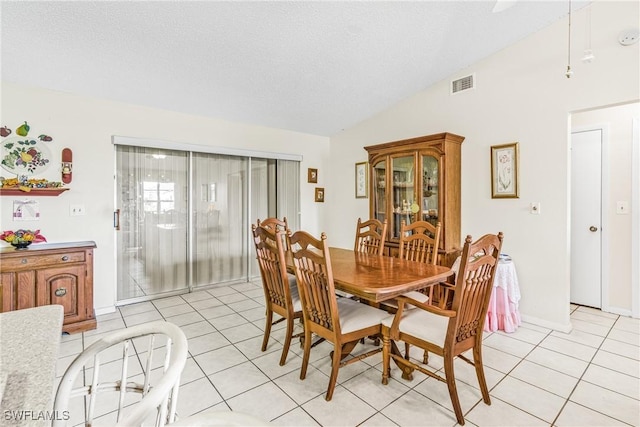 dining room featuring light tile patterned floors, visible vents, a textured ceiling, and lofted ceiling