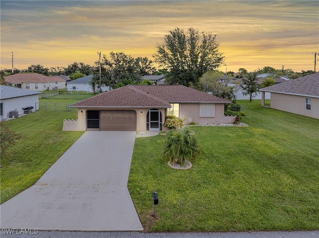 ranch-style home featuring stucco siding, a garage, concrete driveway, and a front lawn