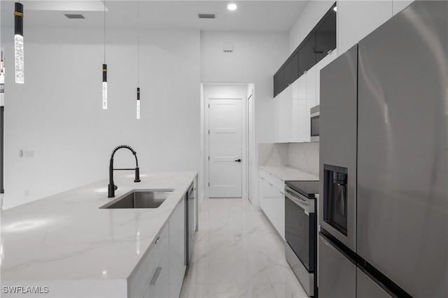 kitchen featuring white cabinets, light stone countertops, sink, pendant lighting, and stainless steel appliances