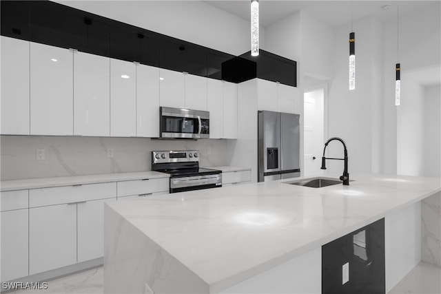 kitchen with white cabinets, an island with sink, sink, pendant lighting, and stainless steel appliances