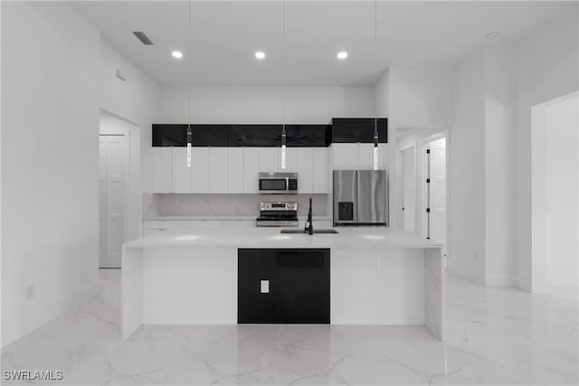 kitchen featuring a spacious island, stainless steel appliances, sink, pendant lighting, and white cabinetry