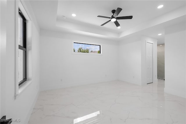 spare room with ceiling fan and a tray ceiling