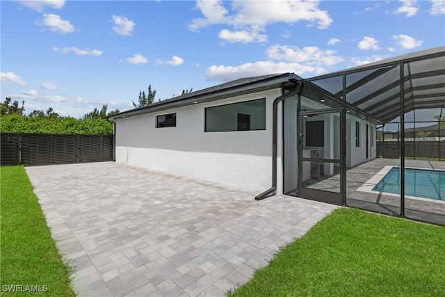 rear view of house featuring a fenced in pool, a patio area, a lawn, and glass enclosure