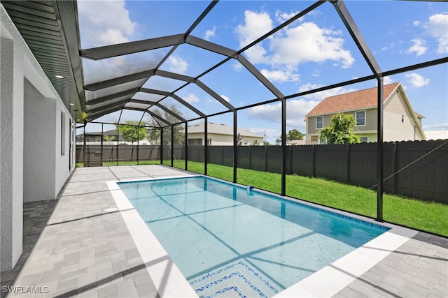 view of swimming pool featuring a yard, a patio area, and a lanai