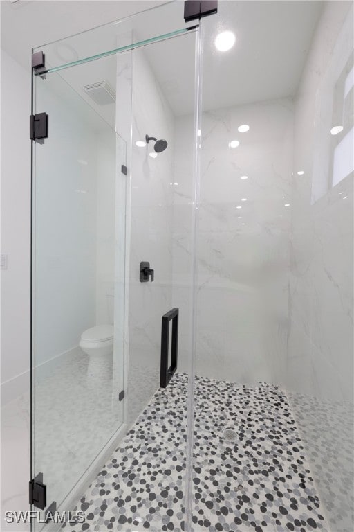 bathroom featuring a shower with door, toilet, and tile patterned flooring