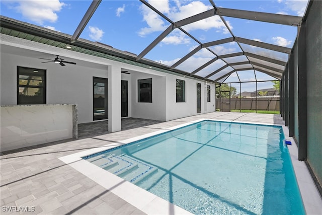 view of swimming pool with a patio, ceiling fan, and glass enclosure