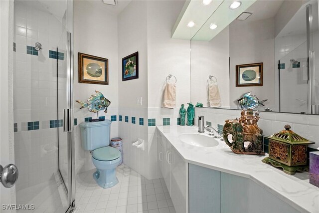 bathroom featuring walk in shower, tile patterned flooring, toilet, vanity, and tile walls