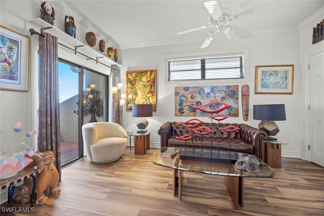 sitting room featuring baseboards, wood finished floors, a ceiling fan, and ornamental molding