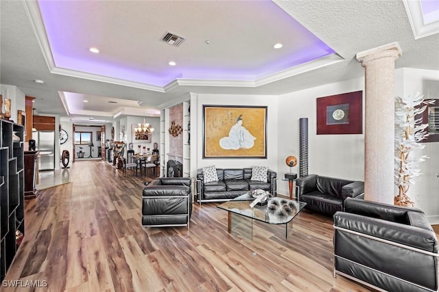 living room with a raised ceiling, decorative columns, and hardwood / wood-style flooring