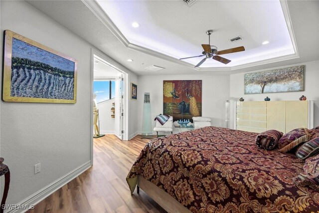 bedroom featuring light hardwood / wood-style floors, ceiling fan, and a tray ceiling