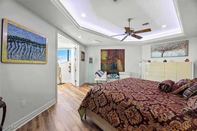 bedroom featuring visible vents, baseboards, a tray ceiling, recessed lighting, and wood finished floors