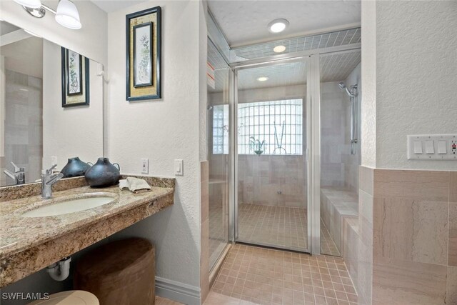 bathroom featuring tile patterned floors, a shower with shower door, and sink